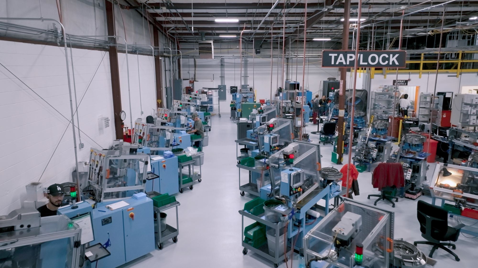 Aerial view of Click Bond’s high-tech manufacturing floor featuring automated equipment and skilled technicians producing adhesive-bonded fasteners.