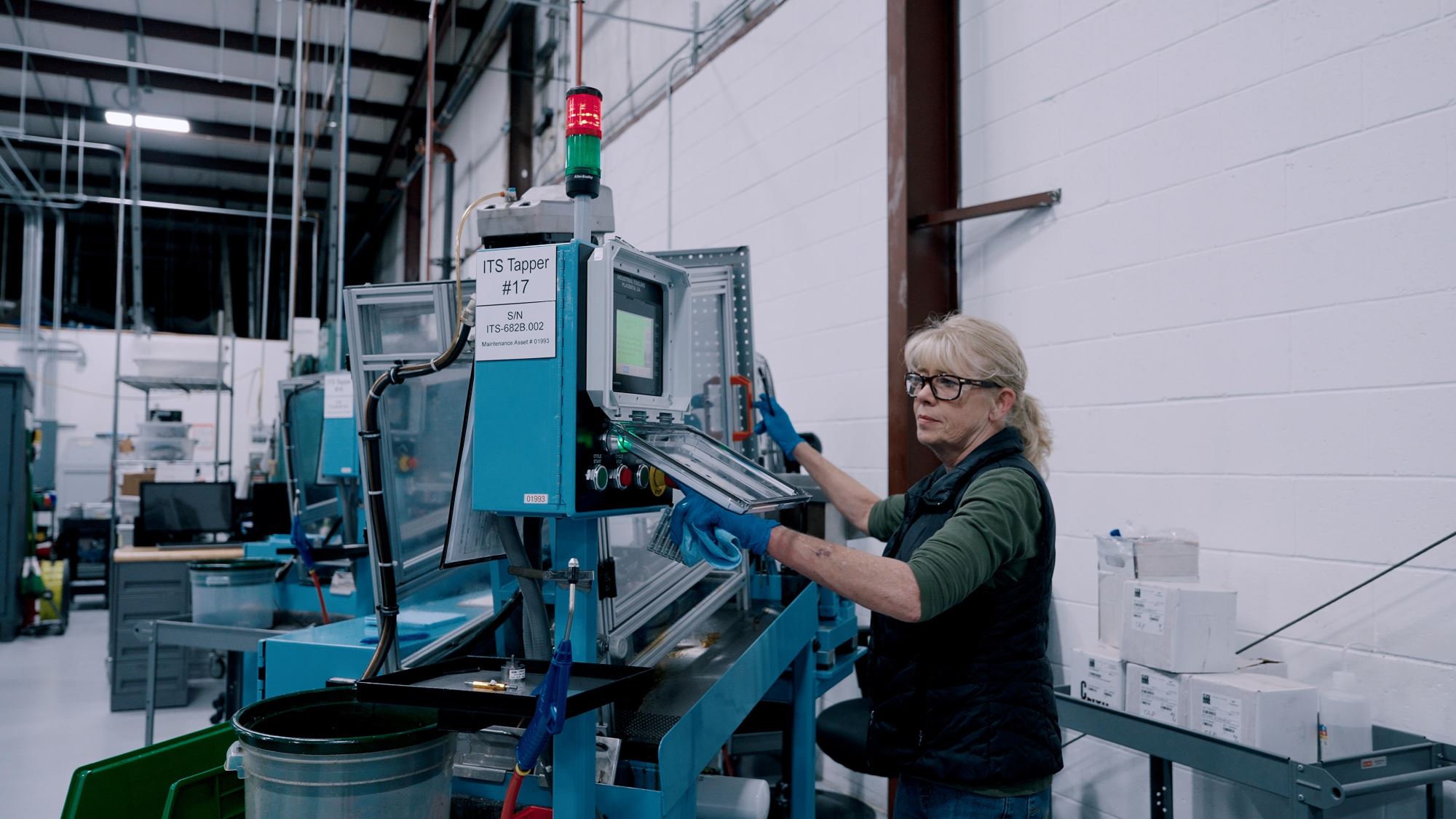 Click Bond technician operating automated tapping machine for precision adhesive fastener manufacturing in a clean, modern production facility.